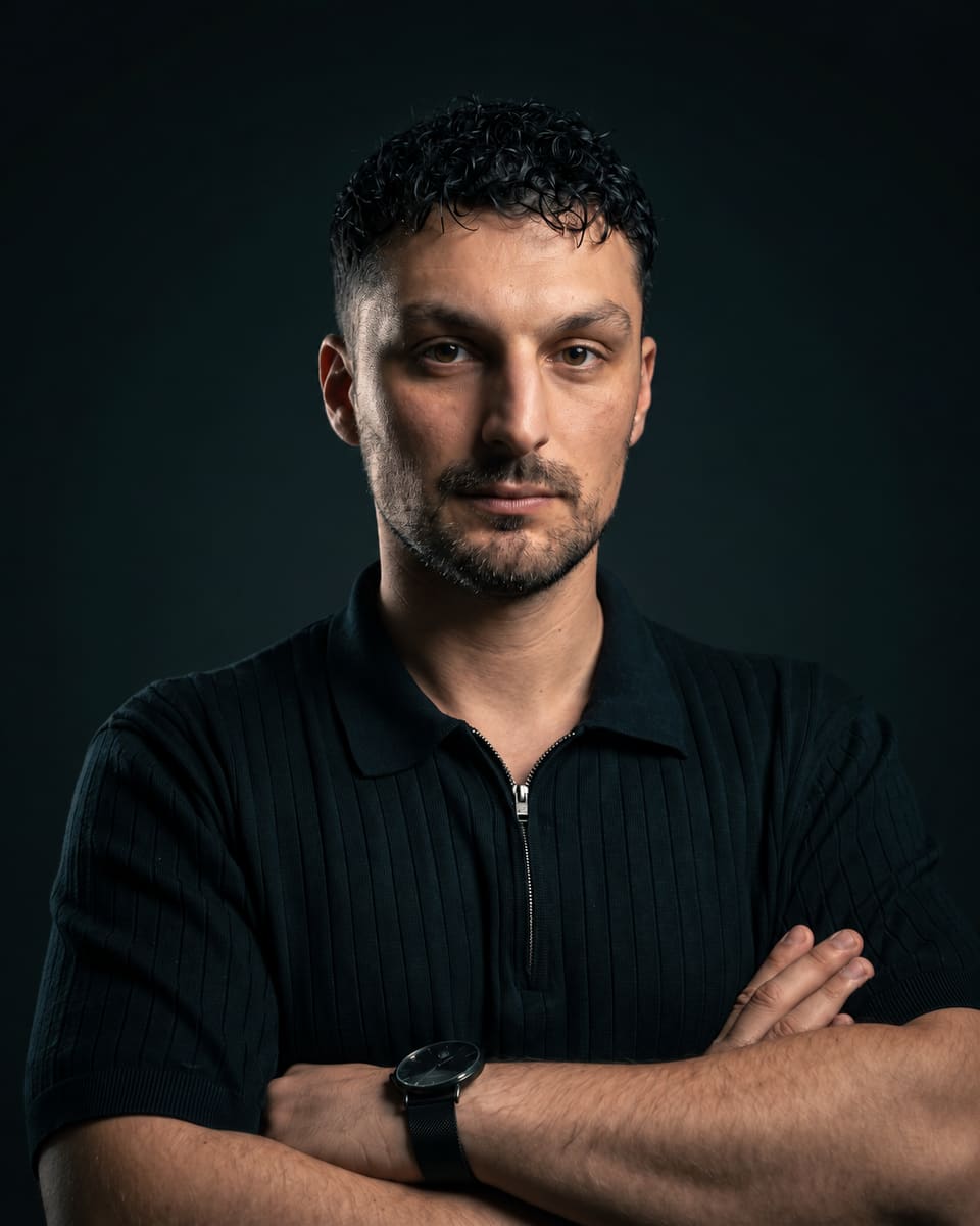 Semih Turna, verschränkte Arme, dunkles Poloshirt vor dunklem Hintergrund